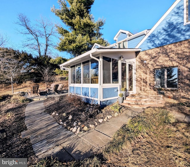 view of property exterior with a sunroom and brick siding