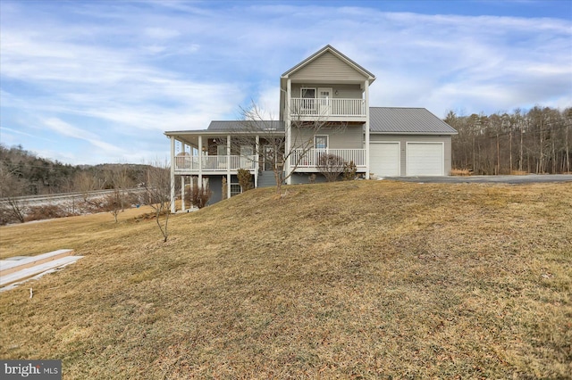 view of front facade with metal roof, a balcony, a garage, covered porch, and a front lawn