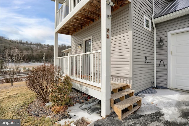 doorway to property with a garage, metal roof, and a porch