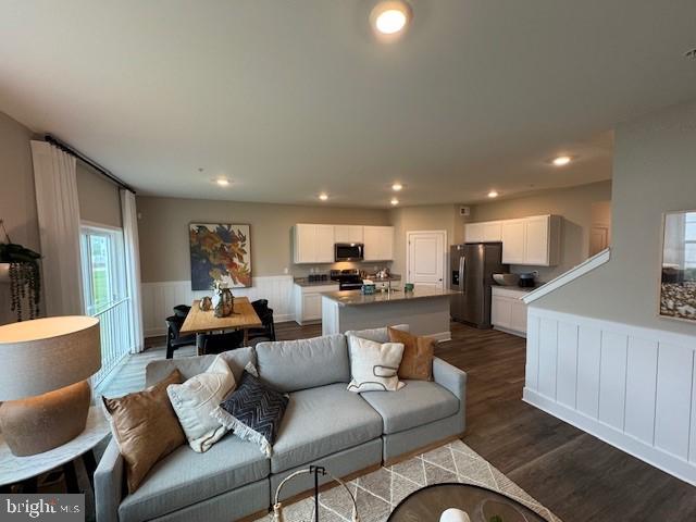 living room with recessed lighting, dark wood-style flooring, and wainscoting