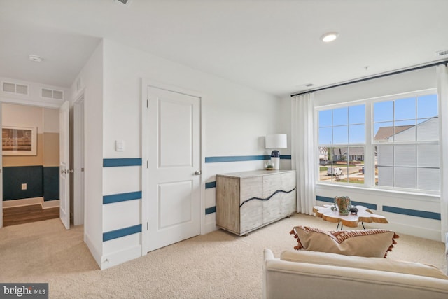 living area with visible vents, light carpet, and baseboards