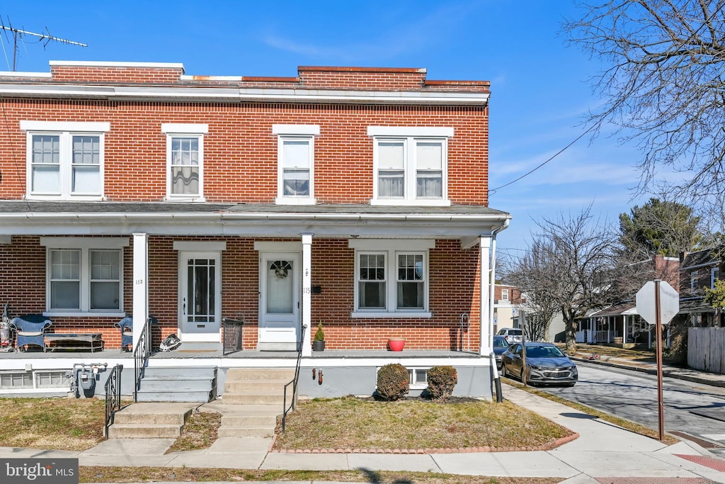 multi unit property with a porch and brick siding