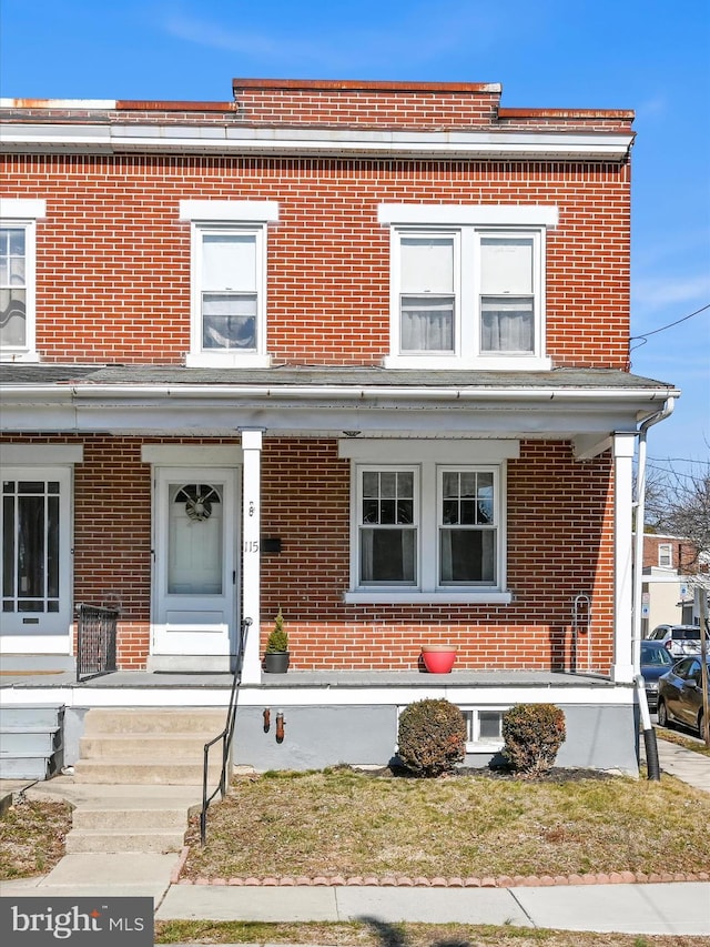 view of front facade featuring brick siding and a porch