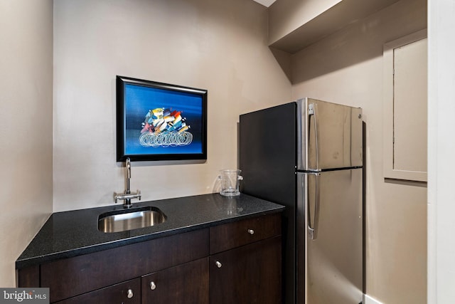 kitchen featuring freestanding refrigerator, a sink, and dark brown cabinetry