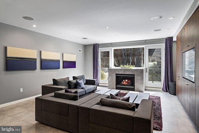 living area with a high end fireplace, plenty of natural light, baseboards, and light tile patterned floors