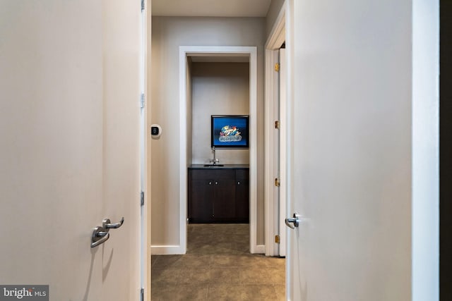 corridor featuring baseboards and a sink