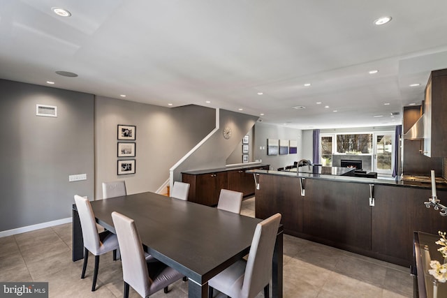 dining space with recessed lighting, a warm lit fireplace, baseboards, and stairs