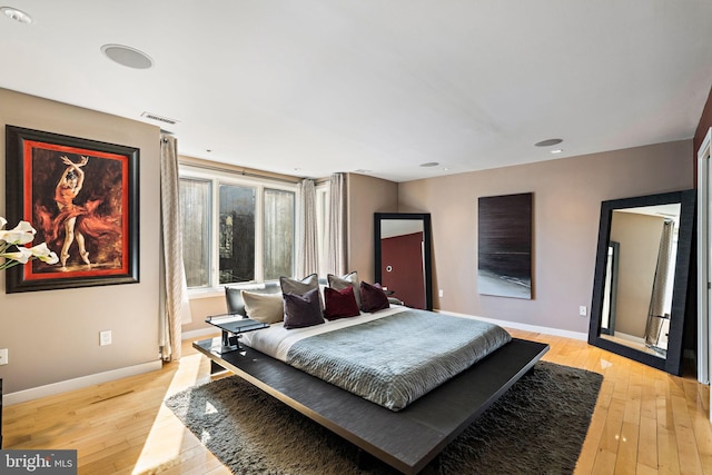 bedroom featuring baseboards, visible vents, and light wood-style floors