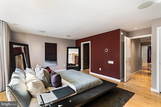 bedroom with light wood finished floors, visible vents, and baseboards