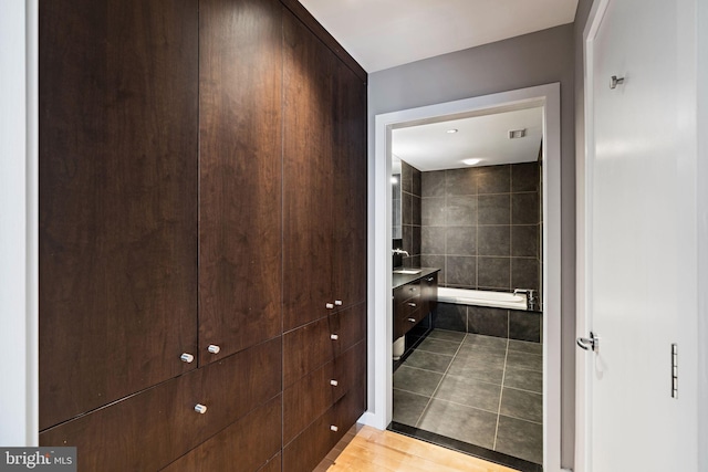 full bath featuring a relaxing tiled tub, visible vents, vanity, and tile patterned floors