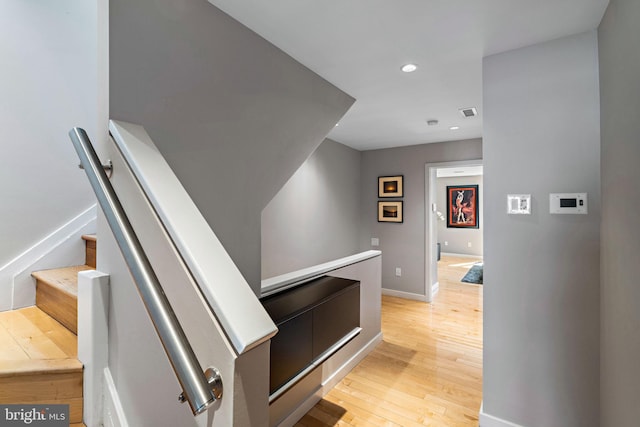 corridor featuring stairs, light wood-type flooring, baseboards, and recessed lighting