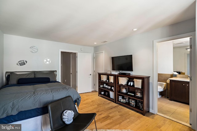 bedroom featuring ensuite bathroom, light wood finished floors, a sink, and recessed lighting