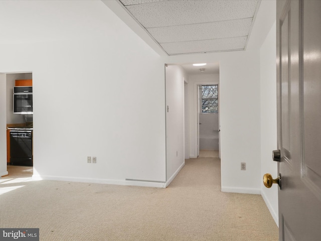 interior space featuring a drop ceiling, baseboards, and light carpet