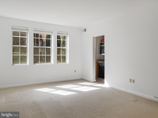 empty room featuring carpet, visible vents, and baseboards