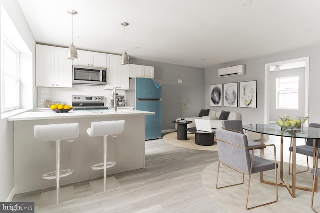 kitchen featuring tasteful backsplash, white cabinets, appliances with stainless steel finishes, light countertops, and a wall mounted AC