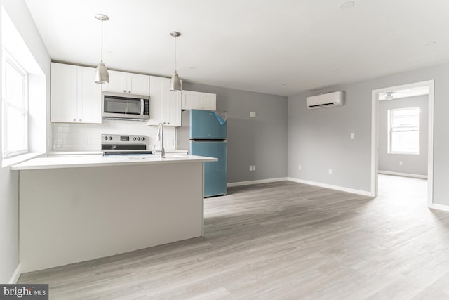 kitchen featuring decorative backsplash, white cabinets, a wall unit AC, light wood-style flooring, and appliances with stainless steel finishes