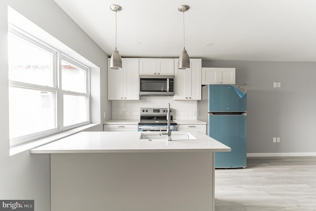 kitchen featuring white cabinetry, light countertops, appliances with stainless steel finishes, hanging light fixtures, and tasteful backsplash