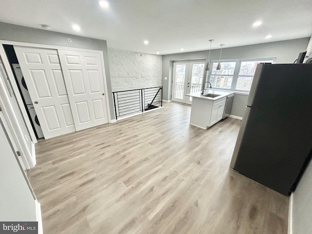 kitchen featuring a sink, light wood-style floors, light countertops, french doors, and freestanding refrigerator