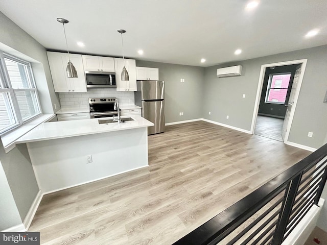 kitchen with tasteful backsplash, white cabinets, appliances with stainless steel finishes, a sink, and a wall mounted AC