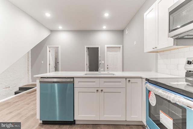 kitchen featuring light wood finished floors, white cabinetry, stainless steel appliances, and a sink