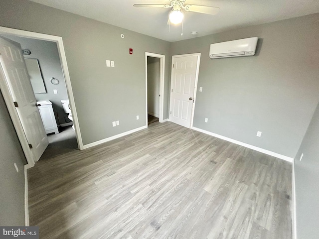 unfurnished bedroom with light wood-style flooring, baseboards, ceiling fan, and a wall mounted AC