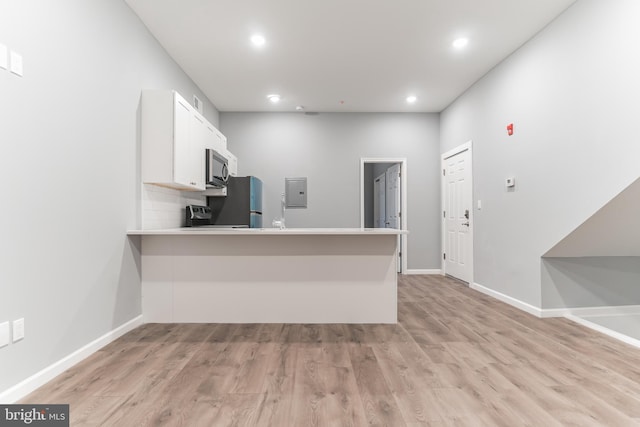 kitchen with freestanding refrigerator, electric panel, white cabinets, and light wood finished floors