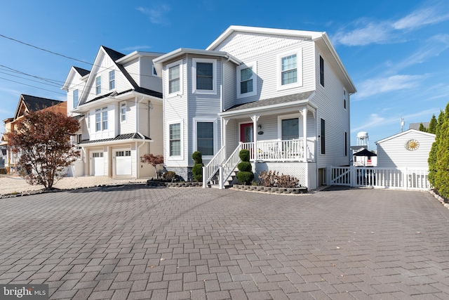 view of front facade with decorative driveway, a porch, and fence