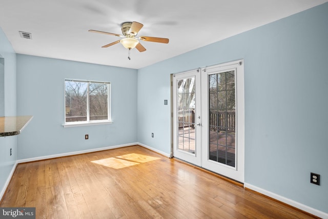 interior space with a wealth of natural light, baseboards, wood-type flooring, and french doors