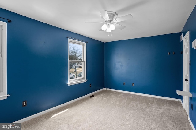 spare room with visible vents, carpet flooring, a ceiling fan, and baseboards