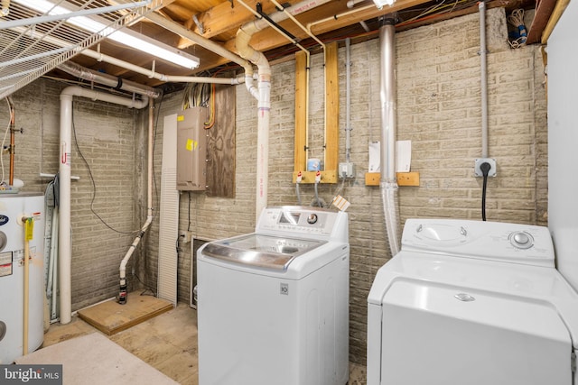 laundry room featuring brick wall, washing machine and dryer, water heater, laundry area, and electric panel