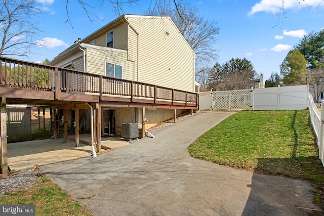 view of property exterior featuring a gate, a fenced backyard, a deck, a patio area, and a lawn