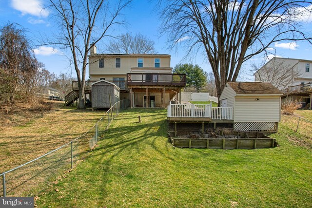 back of house with stairway, a wooden deck, a lawn, an outbuilding, and a storage unit