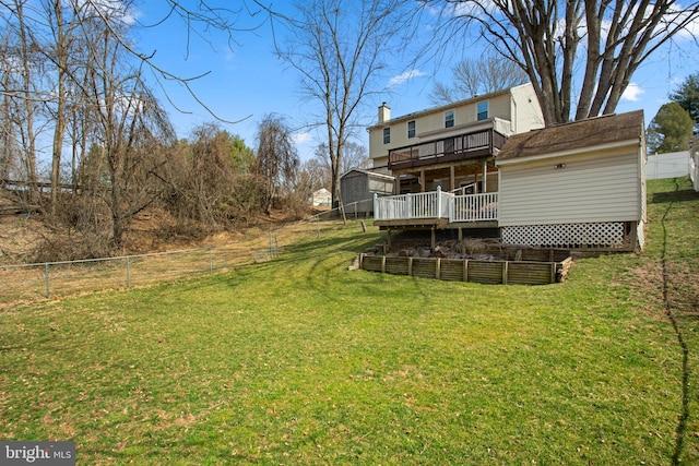 back of house with a vegetable garden, a lawn, fence, and a wooden deck