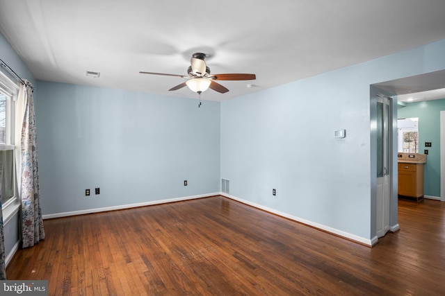 spare room featuring visible vents, baseboards, dark wood-type flooring, and ceiling fan