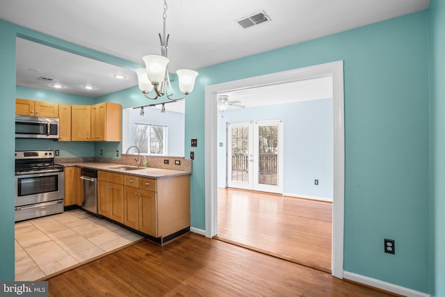 kitchen featuring baseboards, light wood finished floors, visible vents, a sink, and appliances with stainless steel finishes