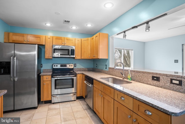 kitchen with a sink, stainless steel appliances, stone counters, and visible vents