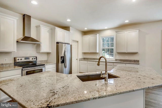 kitchen featuring recessed lighting, a sink, stainless steel appliances, white cabinetry, and wall chimney exhaust hood