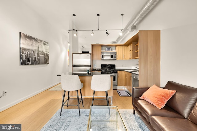 kitchen featuring stainless steel appliances, a kitchen island, open shelves, light wood finished floors, and dark countertops