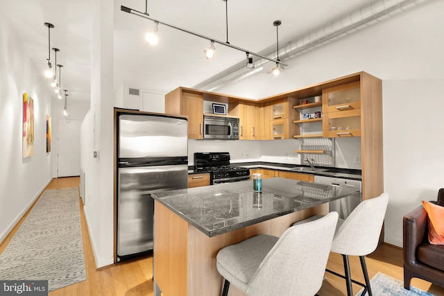 kitchen featuring light wood finished floors, a breakfast bar area, stainless steel appliances, and a sink