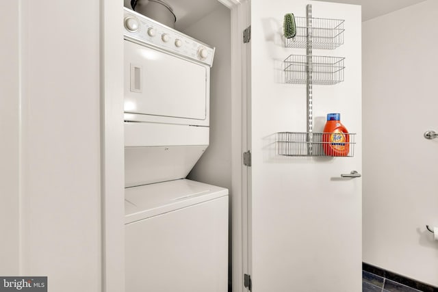 washroom featuring stacked washer and dryer, laundry area, and baseboards