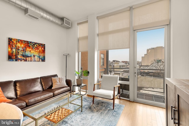 living room with expansive windows, visible vents, and light wood-style flooring