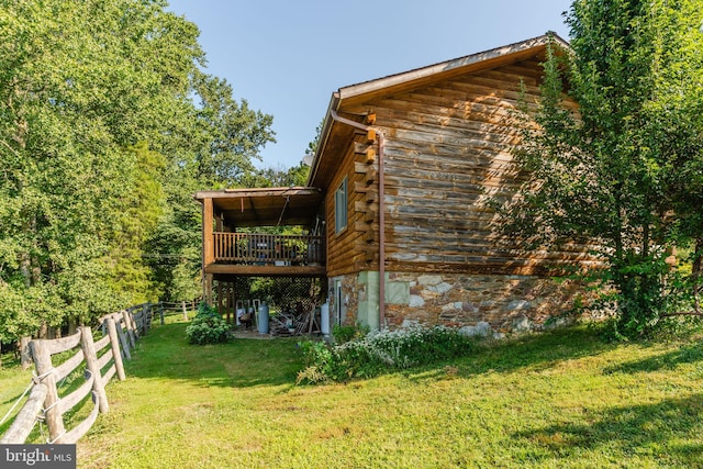 view of side of home with log exterior, a lawn, fence, and a wooden deck