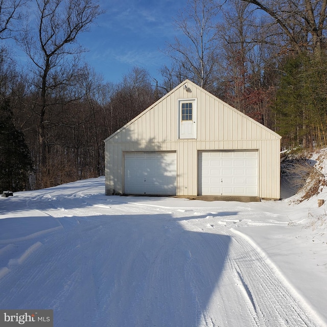 snow covered garage featuring a detached garage