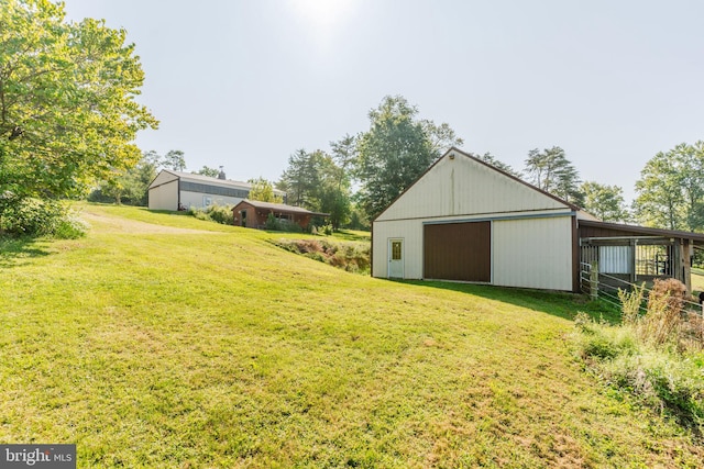 view of yard featuring a garage, an outdoor structure, and an outbuilding