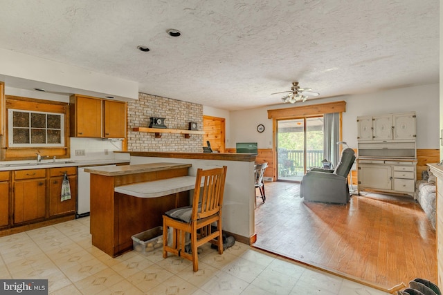 kitchen featuring a sink, light countertops, brown cabinets, light floors, and a kitchen bar