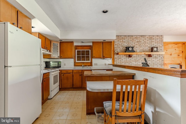 kitchen featuring light countertops, brown cabinetry, a sink, white appliances, and under cabinet range hood