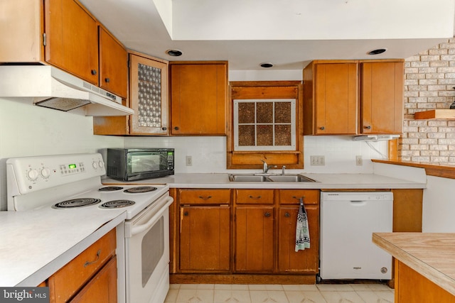 kitchen featuring white appliances, light countertops, a sink, and under cabinet range hood