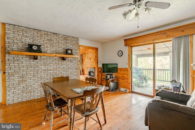 dining area featuring visible vents, a ceiling fan, heating unit, a textured ceiling, and light wood-type flooring