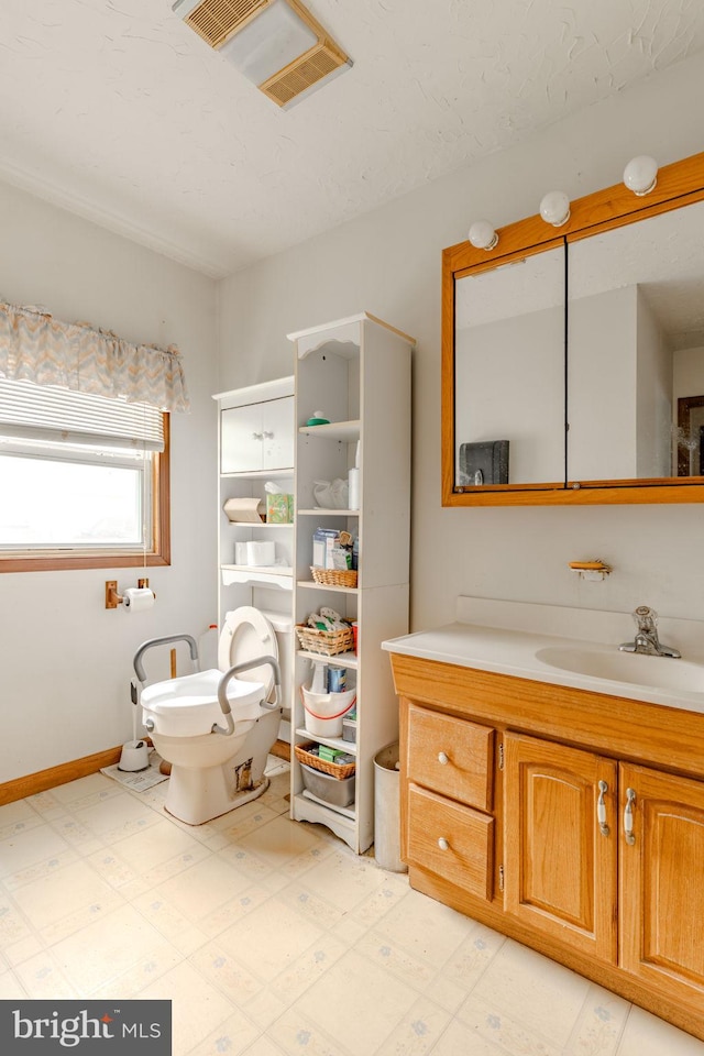 bathroom featuring visible vents, toilet, vanity, baseboards, and tile patterned floors