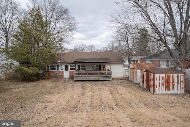 rear view of house featuring dirt driveway, an outbuilding, a storage unit, a wooden deck, and brick siding